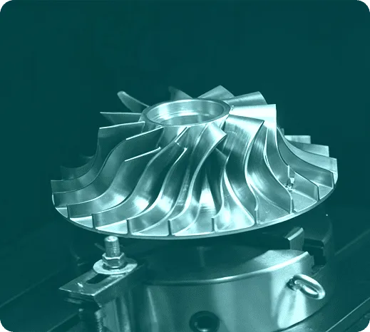 Pieza de mecanizado en acero, mostrando detalles de una turbina con múltiples palas en proceso de fabricación en una máquina CNC.
